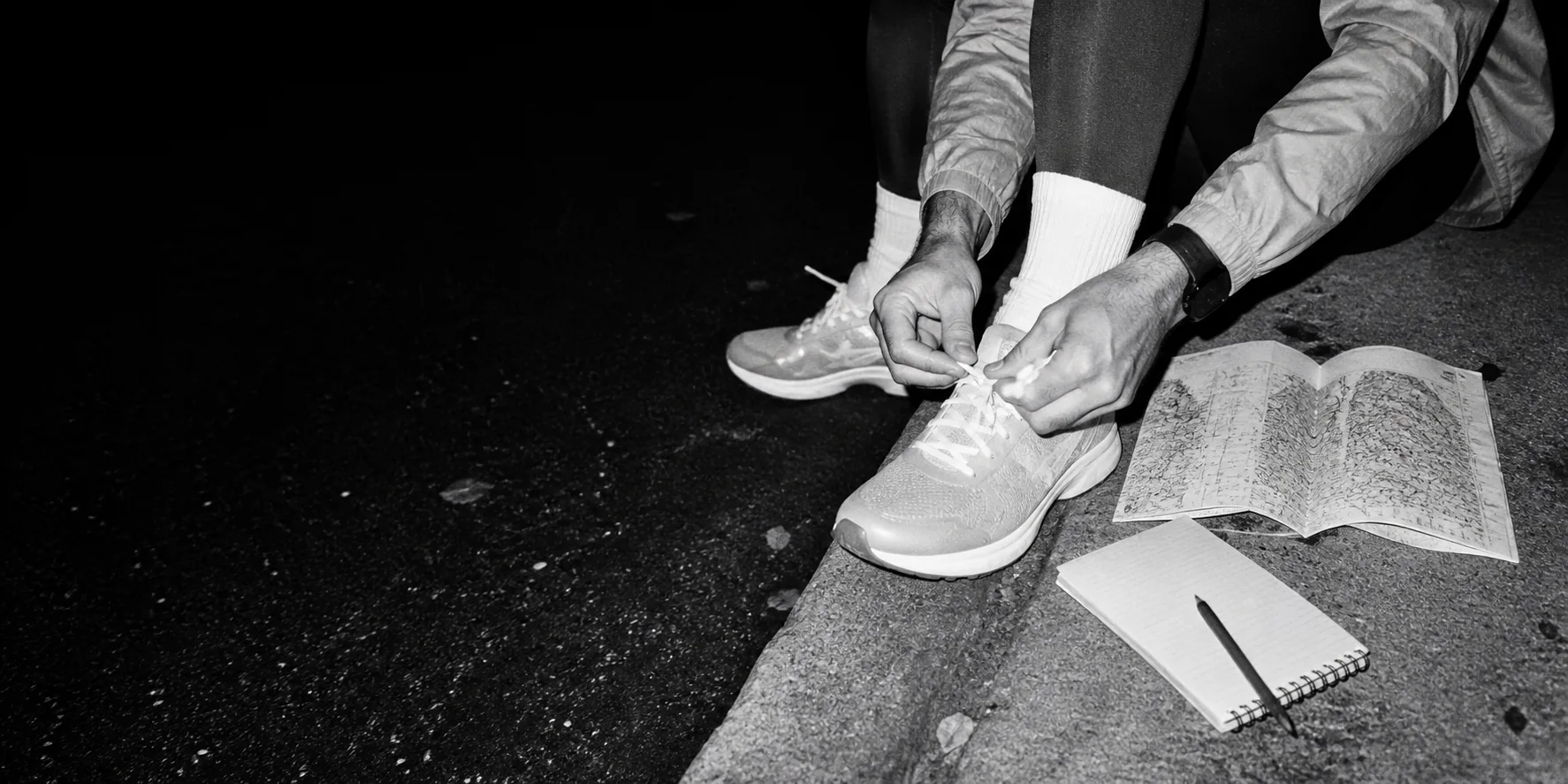 Runner tying a shoe beside a route map and training notebook